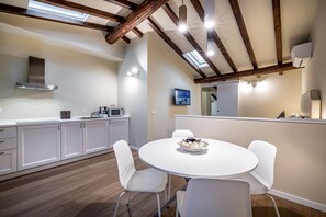 Una cucina moderna con mobili bianchi, un tavolo da pranzo rotondo e un forno integrato.