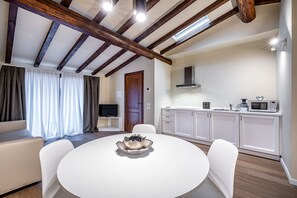 A modern kitchen with white cabinets, a microwave, and a dining area with a white table and chairs. - Garibaldi Palace Petit Penthouse (Prato)