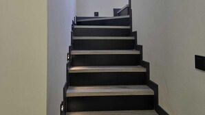 A staircase with a light fixture at the top, a small table, and a window with natural light.