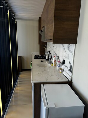 A modern kitchen with a marble backsplash, wooden cabinets, and a white countertop. - Loft Tepe Hotel (Ankara)