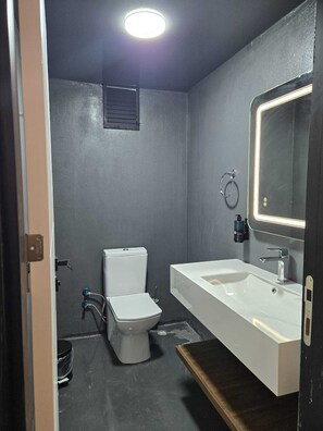 A modern bathroom with a white sink, a mirror with lights, a toilet, and a small window. - Loft Tepe Hotel (Ankara)