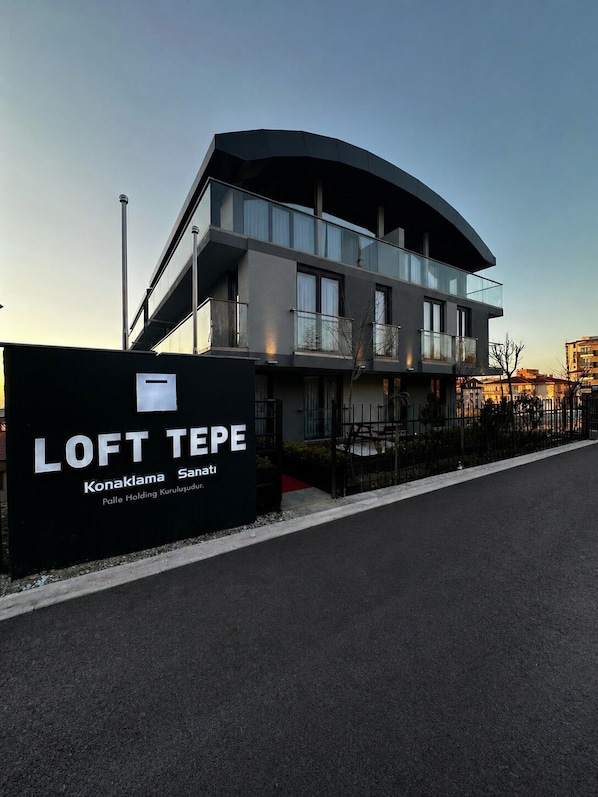 A modern building with a curved facade, balconies, and a sign indicating 'LOFT TEPE' with 'Konaklama' and 'Sani' visible. - Loft Tepe Hotel (Ankara)