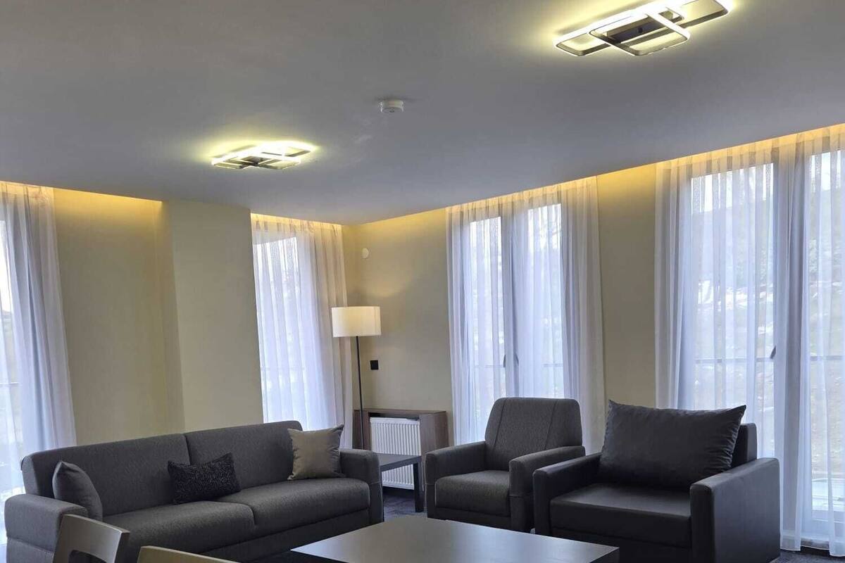 A modern living room with a sofa, chairs, a coffee table, and a lamp.