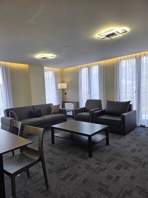 A modern living room with a sofa, chairs, a coffee table, and a lamp. - Loft Tepe Hotel (Ankara)
