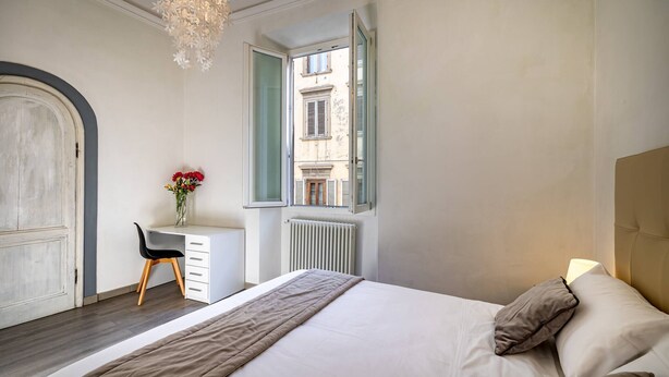 A bedroom with a bed, a desk, and a window. - Duomo collection suites B (Florencia)