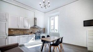 A modern kitchen with white cabinets, a dining table with chairs, and a chandelier. - Duomo collection suites B (Florencia)
