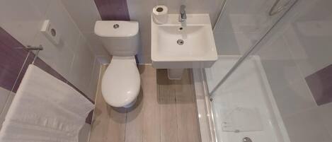 Un baño moderno con inodoro, lavamanos y ducha.
