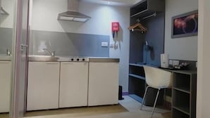 A modern kitchen with white cabinets, a stainless steel sink, and a built-in stove. - London Croydon Hotel (Thornton Heath)