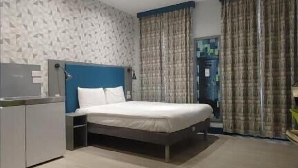 A modern hotel room with a bed, a desk, and a wardrobe. - London Croydon Hotel (Thornton Heath)