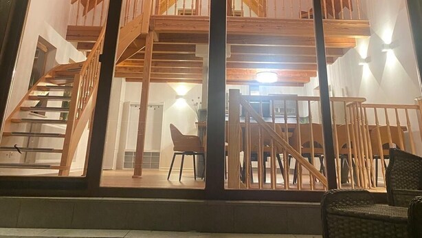 Een houten huis met twee verdiepingen, een balkon en een trap.