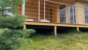 Een modern houten gebouw met een balkon, omringd door groen.