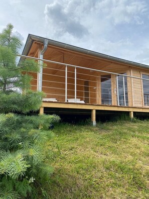 A modern wooden building with a balcony, surrounded by greenery. - Panorama oasis Mäxchen (Güntersberge)