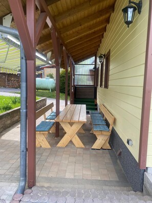 Un espace extérieur abrité, avec des tables et des bancs en bois, un poteau en métal et un lampadaire.