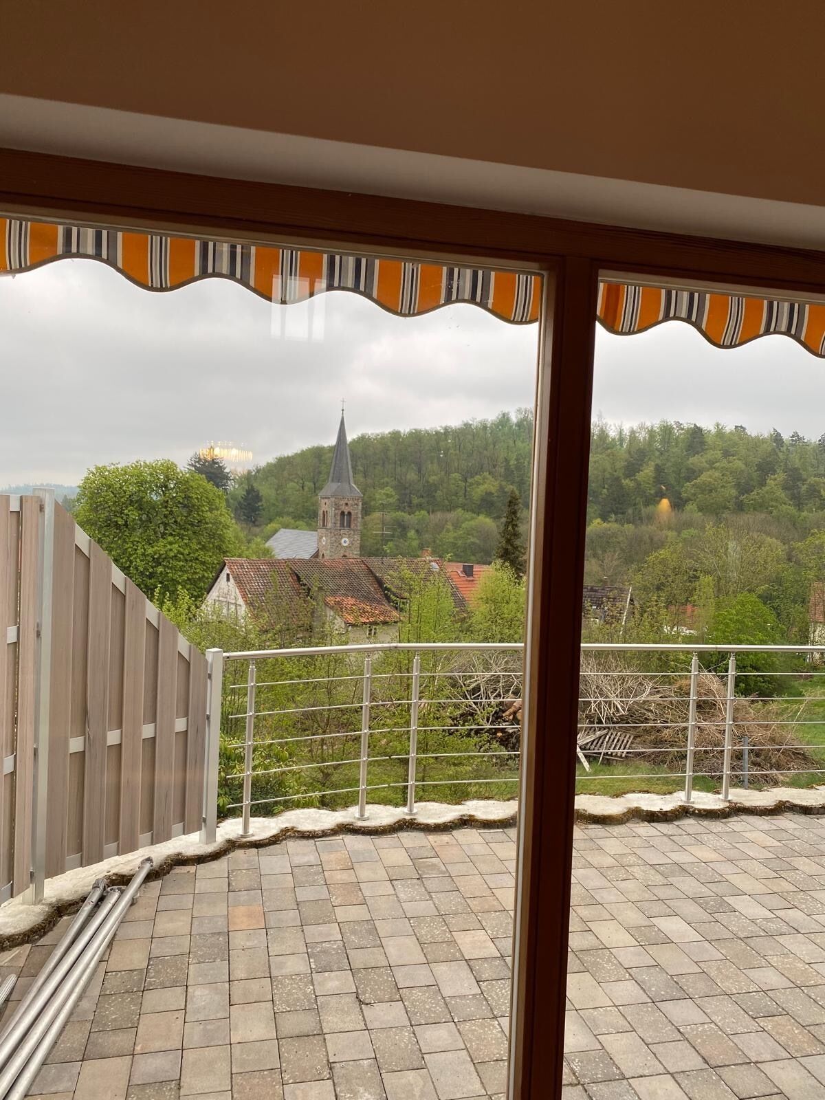Un balcon donnant sur une église et la verdure environnante.