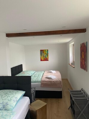 Une chambre à coucher avec un lit, une chaise, une petite table et des œuvres d’art accrochées aux murs.