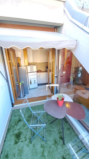 Un petit espace extérieur aménagé avec une table, des chaises et un étendoir.