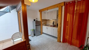 Una cocina compacta con armarios de madera, un refrigerador y una cafetera.