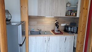 Una cocina compacta con lavamanos integrado, cafetera, tostadora y microondas.