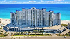 A high-rise hotel with a central courtyard, located near a beach with a clear blue sky. - Beachfront- Amazing Views-Lighthouse 310 (Gulf Shores)