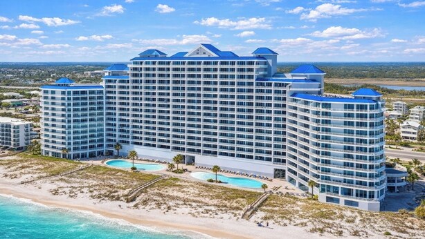 A large, multi-story hotel with a curved facade, multiple balconies, and a pool area. - Beachfront- Amazing Views-Lighthouse 310 (Gulf Shores)