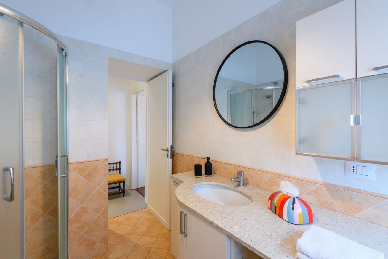 Une salle de bain équipée d’une douche, d’un lavabo, d’un miroir et de placards.