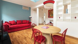 A modern living room with a red sofa, wooden dining table, and red chairs.