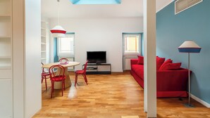 A living room with a TV, red furniture, a skylight, and a red couch.