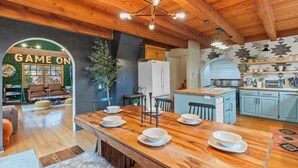 A spacious kitchen with wooden cabinets, a central island, and a dining area with a wooden table and chairs. - Spacious Family Cabin w/Hot Tub & Mountain Views (Tehachapi)
