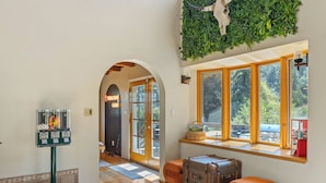 A hotel lobby with a reception desk, a window seat with a view, and a wall-mounted plant. - Spacious Family Cabin w/Hot Tub & Mountain Views (Tehachapi)