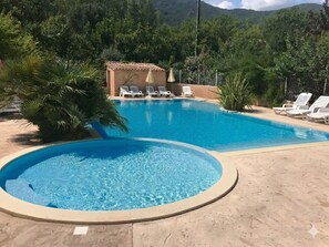 A swimming pool with lounge chairs and a small building with a tiled roof.