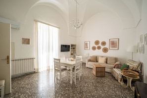 A spacious living area with a dining table, sofa, and a television. - Casa Pascal with Panoramic Terrace in Central Ostuni (Ostuni)
