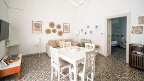 Een moderne woonkamer met een witte bank, een eettafel en een kroonluchter.
