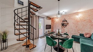 Un interno moderno con una scala a chiocciola, un'area pranzo con sedie verdi e un divano.