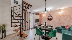 A modern interior with a spiral staircase, a dining area with green chairs, and a sofa. - Villa Anna by Villas Guide (Vela Luka)