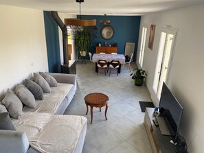 Ein Wohnzimmer mit Sofa, Couchtisch, Fernseher und einem Essbereich mit Tisch und Stühlen.