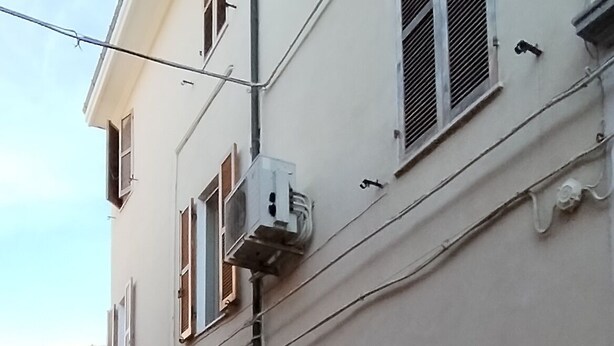A narrow cobblestone street lined with buildings featuring traditional architecture, including shuttered windows and a visible number '25' on one building. - Gatto errante (Pesaro)