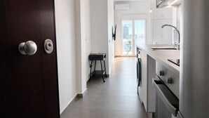 A modern kitchen with stainless steel appliances, a small dining area, and a view of the city through large windows. - Athens View Studio Near Lycabettus Hill by MPS (Athina)