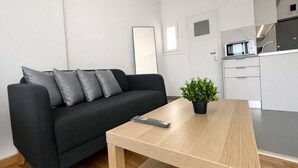 A modern living room with a black sofa, a wooden coffee table, and a small potted plant. - Athens View Studio Near Lycabettus Hill by MPS (Athina)
