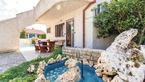 Ein Steinhäuschen mit Swimmingpool, Gartenmöbeln und einer Felsformation.