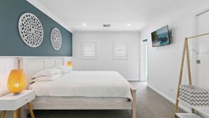 Ein modernes Schlafzimmer mit einem Bett, zwei Wanddekorationen, einem Gemälde und einer Holzleiter.
