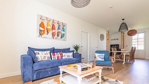 A living room with a blue sofa, a coffee table, a rug, and a painting on the wall. - Holiday Home “Captiva” with Wi-Fi (Saint-Georges-d'Oléron)