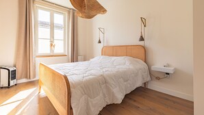 A bedroom with a bed, a window with curtains, a wall-mounted shelf, and a hanging light fixture. - Holiday Home “Captiva” with Wi-Fi (Saint-Georges-d'Oléron)