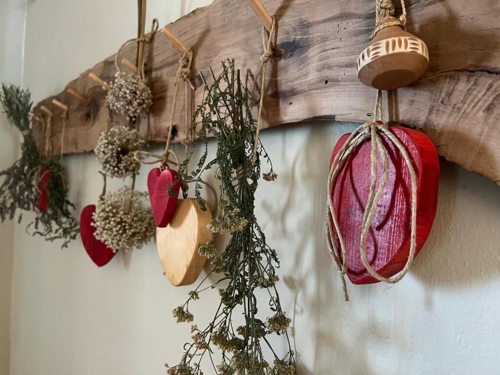 Un élément de décoration murale de style rustique, avec des éléments en bois et en rouge, notamment une cloche et des objets en forme de cœur.