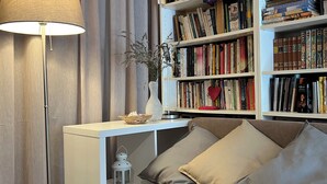 Un'accogliente zona giorno con un divano, una lampada da terra, una libreria e un tavolino con oggetti decorativi.