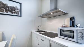 Ett modernt kök med inbyggd mikrovågsugn, en köksfläkt i rostfritt stål och en diskho.
