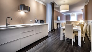 Una cocina moderna con microondas integrado, campana extractora de acero inoxidable y comedor con mesa y sillas blancas.
