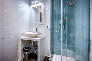 A modern bathroom with a white sink, mirror, and glass-enclosed shower. - Garibaldi Palace The Romantic (Prato)
