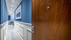 A hallway with a wooden door, a mirror, and a blue bench. - Garibaldi Palace The Blue Charme (Prato)