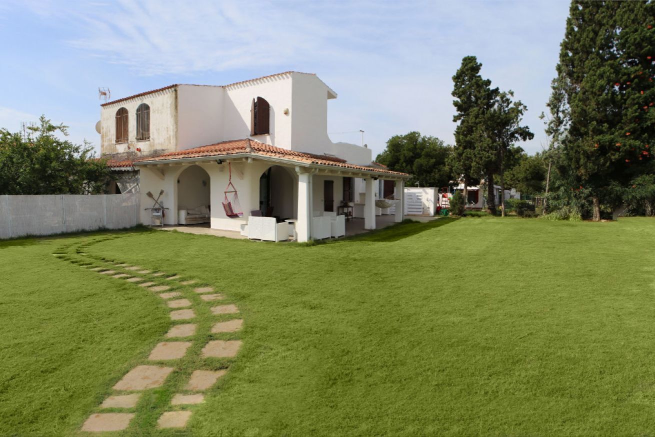 Um edifício branco com telhado em azulejos e um jardim com caminho de pedra.