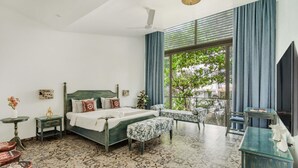A bedroom with a bed, bedside tables, a bench, a desk, and a window with curtains. - Nerul Nirvana Nest by Dia Hotels (Nerul)